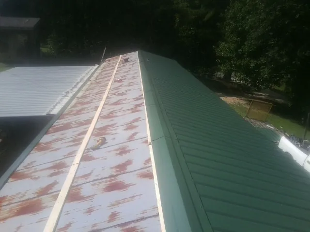 Old rusted panels beside newly installed green metal roofing — Wind Damage Roof Repair by Roofing Brothers in Echo
