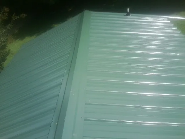 New green metal panels meeting at the ridge of a roof — Flat Roof Repair work by our crew in Echo